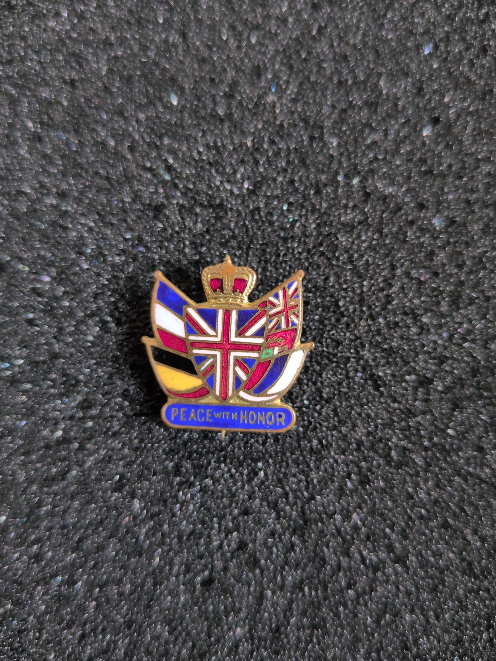 This is a 1914-1915 "Peace with Honor" patriotic flag pin issued by the British
